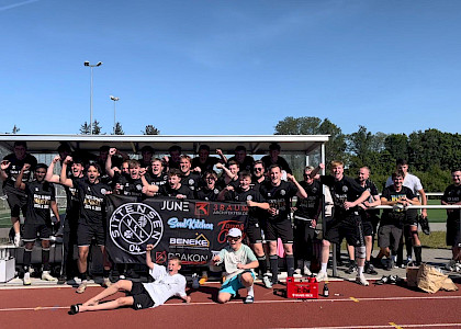 die erste Herren stehen zusammen im Tor und jubeln über ihre Meisterschaft. Sie halten einen VfL-Banner hoch.