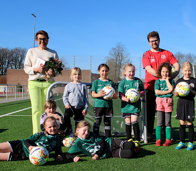 Sponsorenbild mit einer Gruppe junger Fußballerinnen, die neue Fußbälle in der Hand halten und gemeinsam mit ihrem Trainer ein Geschenk an die Sponsorin überreichen. Sponsorenbild mit einer Gruppe junger Fußballerinnen, die neue Fußbälle in der Hand halten und gemeinsam mit ihrem Trainer ein Geschenk an die Sponsorin überreichen.
