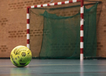 auf dem Foto sieht man einen Handball in der Halle auf dem Boden vor einem Handballtor liegen