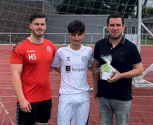 Foto mit dem Trainer Marcel Skrzypek, einem Spieler im neuen Trikot und dem Sponsor, der Sponsor hält das Geschenk und alle freuen sich