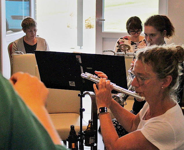 Gruppe an Musikerinnen, die gemeinsam musizieren. Eine Frau spielt mit der Querflöte