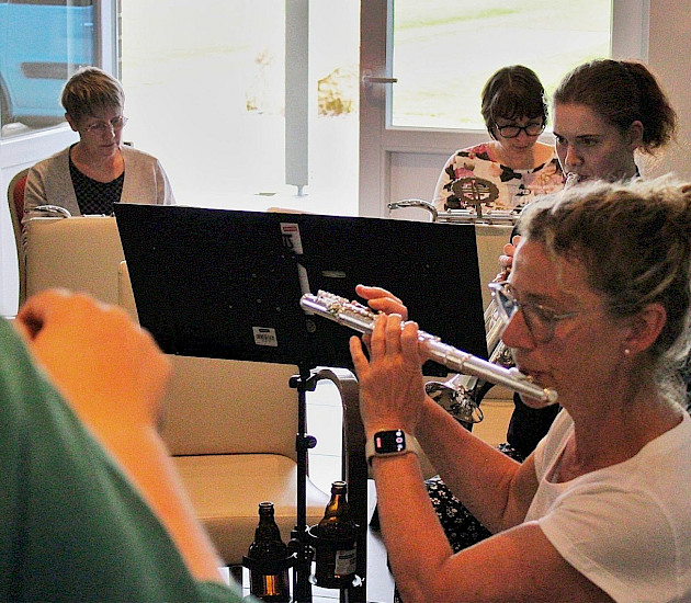 Gruppe an Musikerinnen, die gemeinsam musizieren. Eine Frau spielt mit der Querflöte