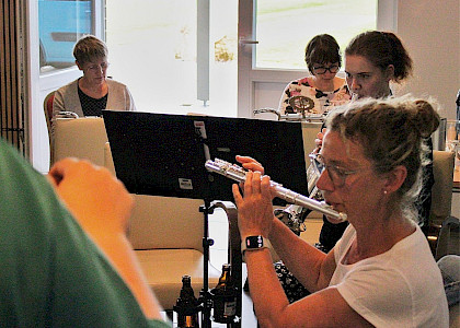 Gruppe an Musikerinnen, die gemeinsam musizieren. Eine Frau spielt mit der Querflöte