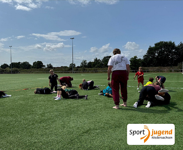 Kinder mit der Judolehrerin, die ihnen Fallübungen zeigt. die Kinder üben mit einem Partner oder Partnerin