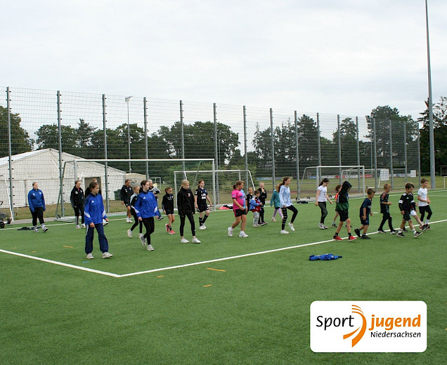 Kinder und Trainerin tanzen Linedance auf dem Sportplatz