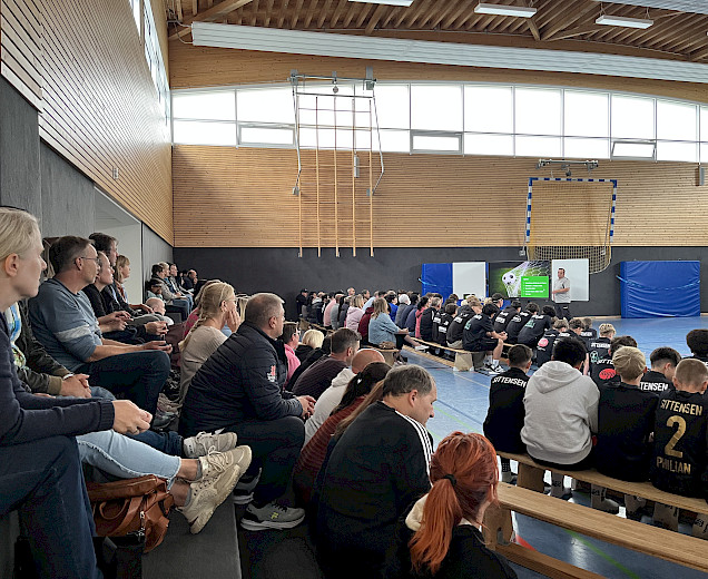 Elternabend in der Sporthalle mit vielen Eltern und Spielern, die auf den Bänken und auf der Tribüne sitzen