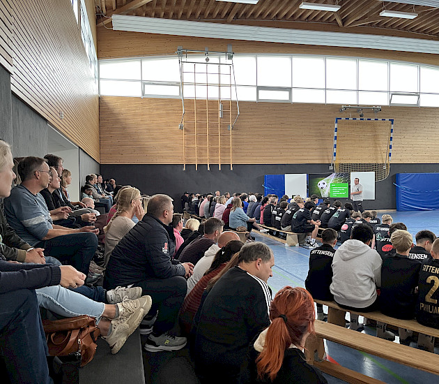 Elternabend in der Sporthalle mit vielen Eltern und Spielern, die auf den Bänken und auf der Tribüne sitzen
