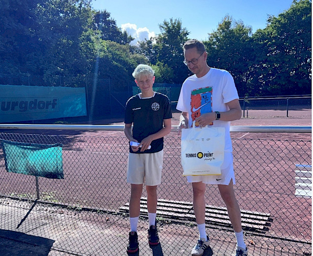 Jakob steht mit einem Trainer auf dem Tennisplatz und erhält eine Auszeichnung Jakob steht mit einem Trainer auf dem Tennisplatz und erhält eine Auszeichnung