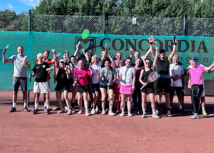 Tennisgruppe, die beim Jubiläum zusammensteht und alle haben die Arme nach oben, weil sie sich freuen