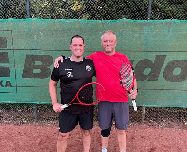 2 Tennisspieler umarmen sich auf dem Tennisplatz nebeneinander mit den Schlägern in der Hand.