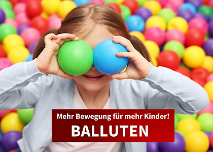 kind im bällebad mit zwei kleinen bällen vor den augen