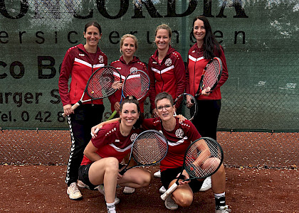 Tennisdamen in einer Gruppe mit Tennisschlägern auf dem Tennisplatz