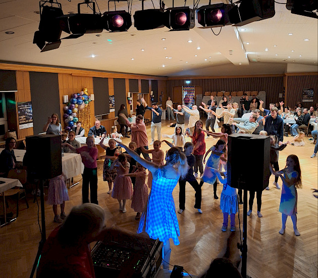 Viele Menschen in einem Raum bei der Inklusionsdisko, die gemeinsam feiern und alle die Arme hochnehmen zum gemeinsamen Tanz Viele Menschen in einem Raum bei der Inklusionsdisko, die gemeinsam feiern und alle die Arme hochnehmen zum gemeinsamen Tanz