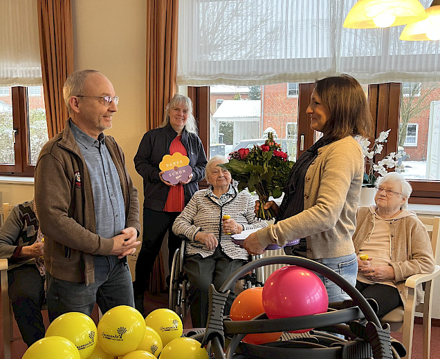 Übergabe einen Blumenstrausses an die Pflegedienstleitung vor Sportgeräten