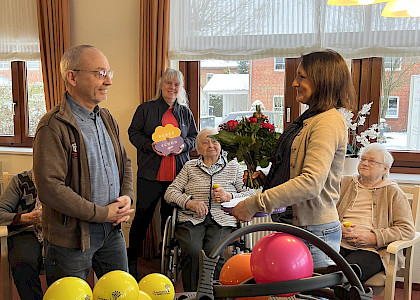 Übergabe einen Blumenstrausses an die Pflegedienstleitung vor Sportgeräten