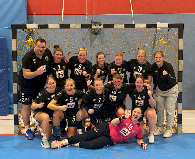 Handball-Damen-Team steht mit ihrem Trainer im Tor und bejubeln den Sieg