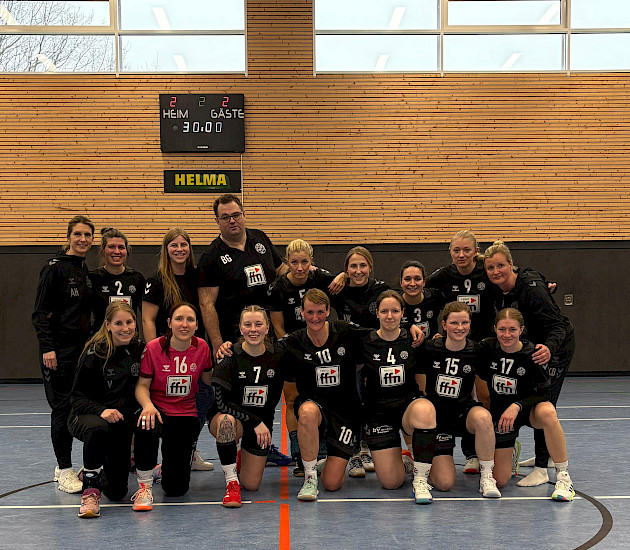 In der Halle hocken die Damen in 2er Reihe zusammen und der Trainer steht hinten in der Mitte