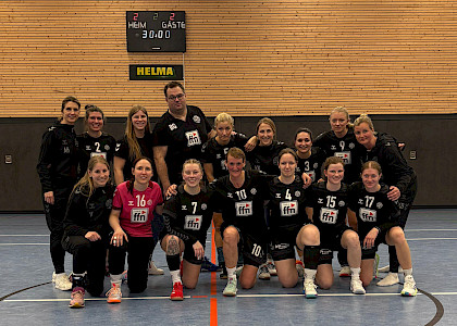 In der Halle hocken die Damen in 2er Reihe zusammen und der Trainer steht hinten in der Mitte