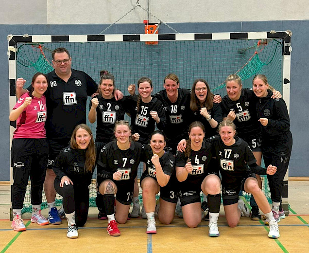 Handballdamen stehen mit ihrem Trainer im Tor der Tostedter Halle und freuen sich über ihren Sieg