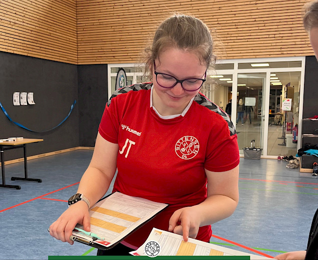 Eine Übungsleiterin zeigt auf den Papierbogen der Sportabzeichenabnahme Eine Übungsleiterin zeigt auf den Papierbogen der Sportabzeichenabnahme