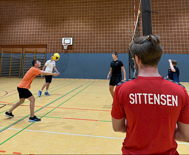 Trainer am Volleyballnetz vor Spielern