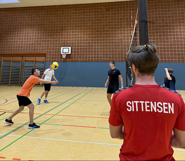 Trainer am Volleyballnetz vor Spielern Trainer am Volleyballnetz vor Spielern