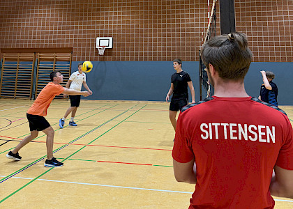 Trainer am Volleyballnetz vor Spielern Trainer am Volleyballnetz vor Spielern
